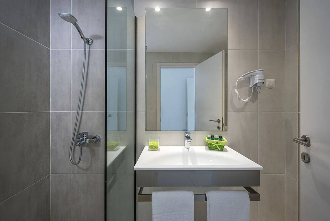 Badezimmer im Alexander House mit einer Glasdusche, einem Waschbecken und einem Haartrockner.