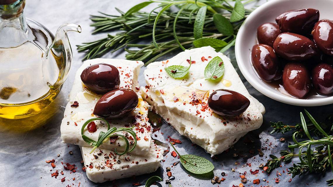 Alexander House Essen auf einem Tisch mit Feta, Oliven, Kräutern und Gewürzen.