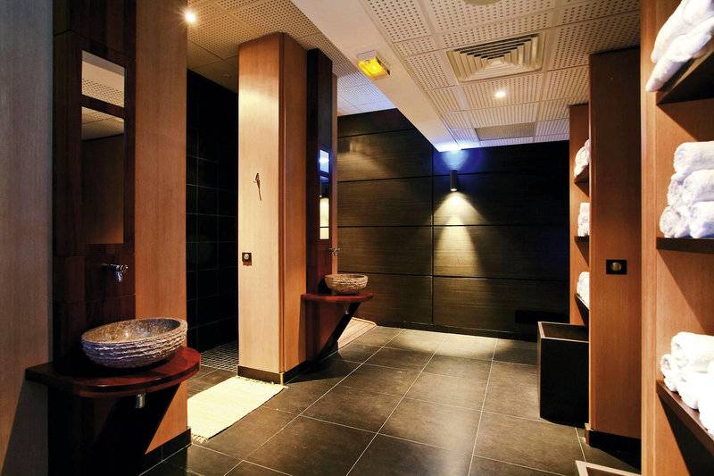 Innenansicht der Dusche im La Creole Beach Hotel & Spa mit runden Waschbecken und Holzschränken.