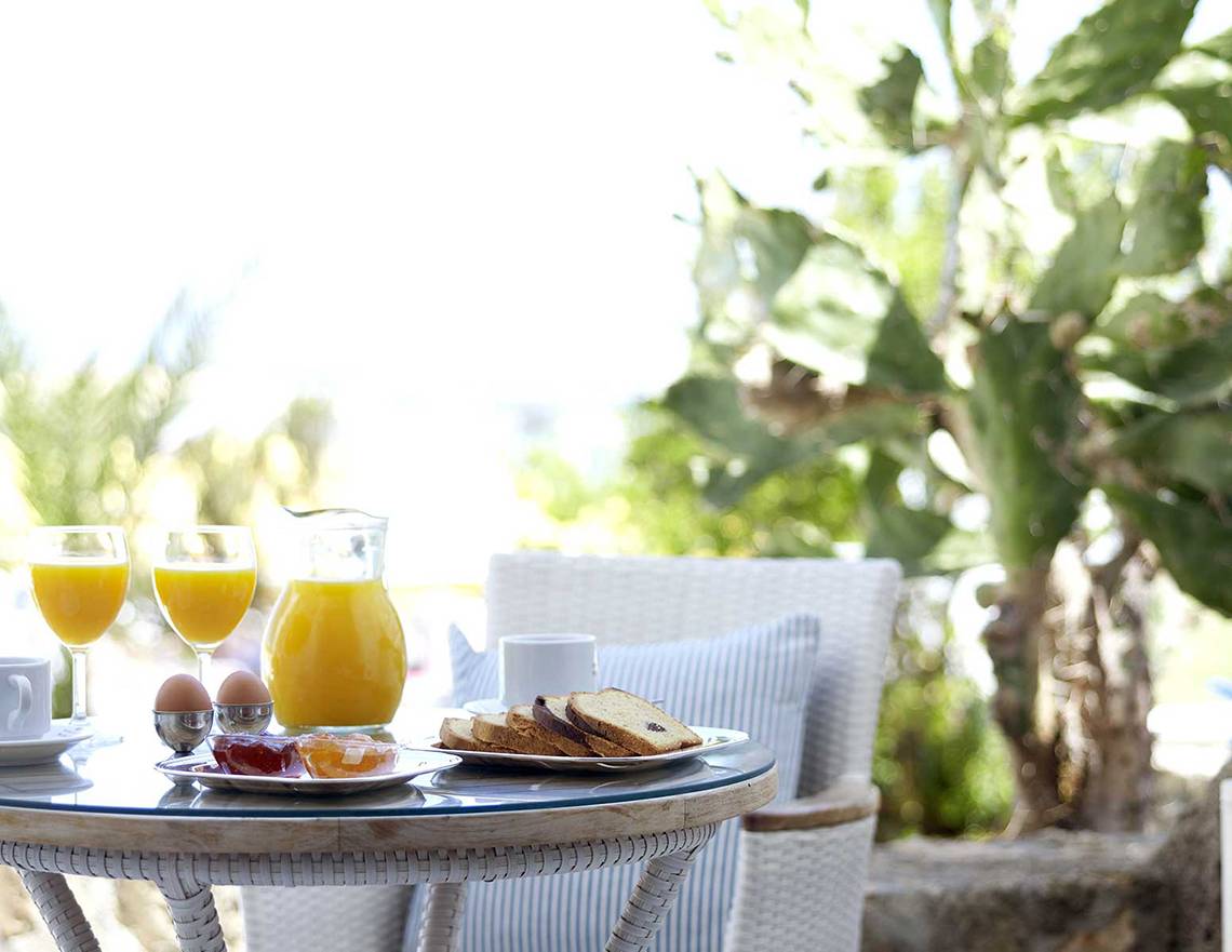 Frühstückstisch im Freien mit Orangensaft, Eiern und Brötchen im Serita Beach Hotel.