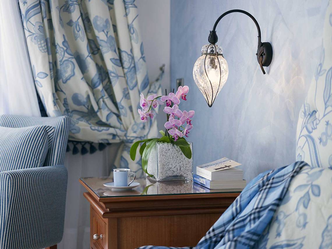 Serita Beach Hotel Zimmer mit Nachttisch, Orchideen, Bücher und Wandlampe.