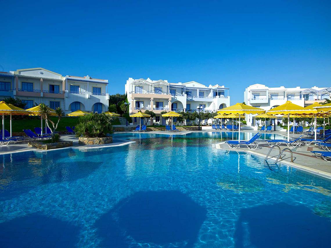 Ein Pool im Serita Beach Hotel mit blauen Liegestühlen und gelben Sonnenschirmen.