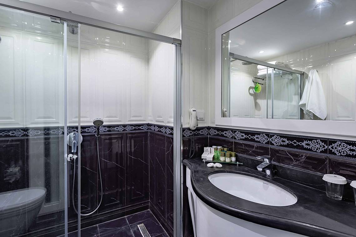 Badezimmer im Asteria Family Resort Side mit Duschkabine, Waschbecken und Spiegel.