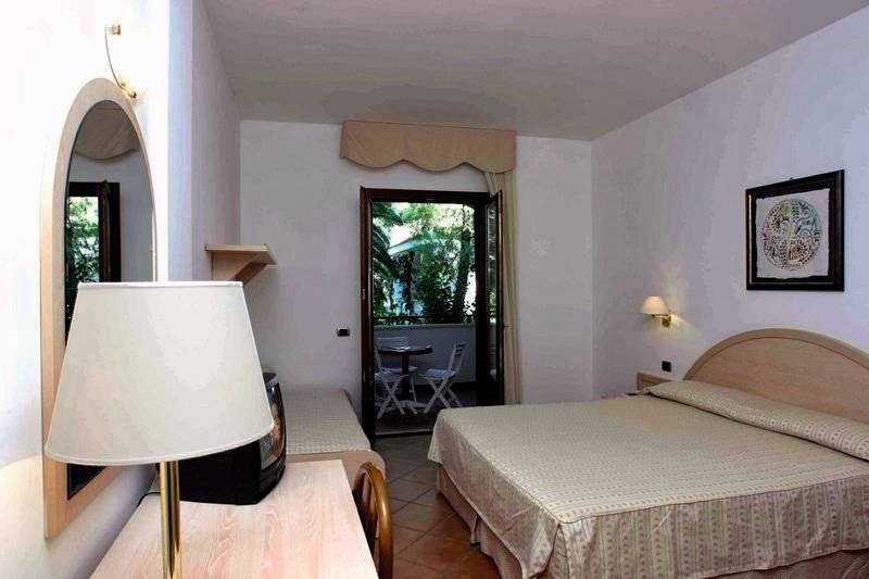 Gabbiano Beach Vieste Hotelzimmer mit Bett, Tisch, Stühlen und Spiegel.