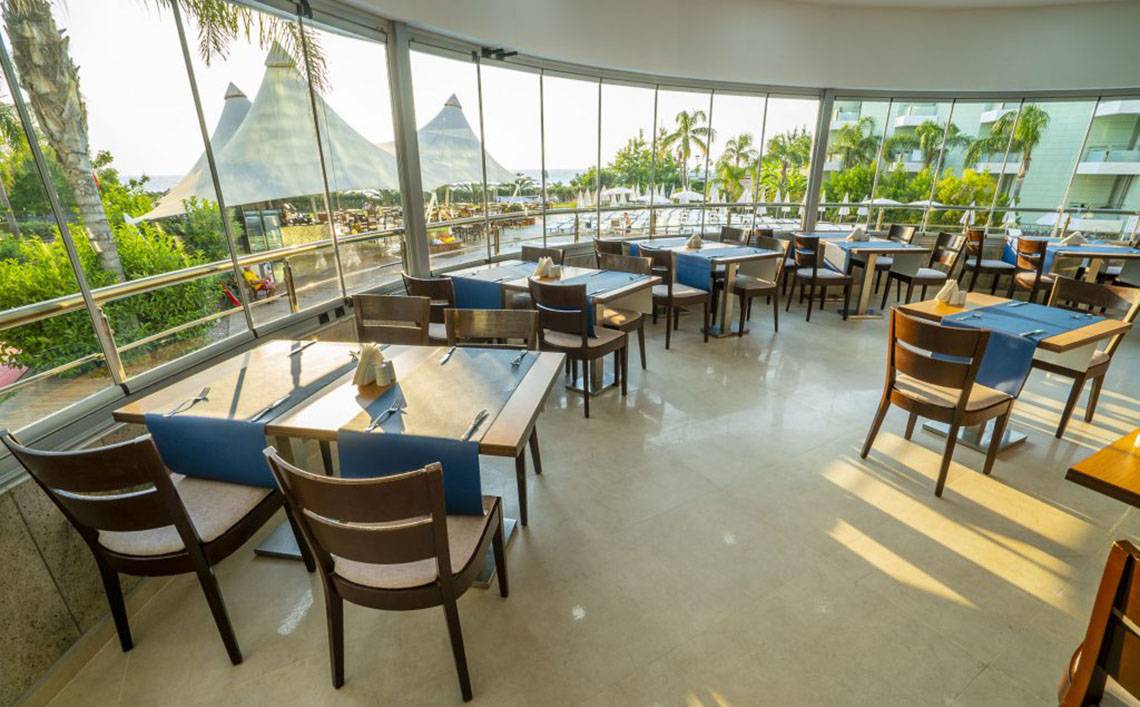 Innenansicht des Restaurants im Grand Belish Resort Hotel & Spa mit runden Tischen und Stühlen.