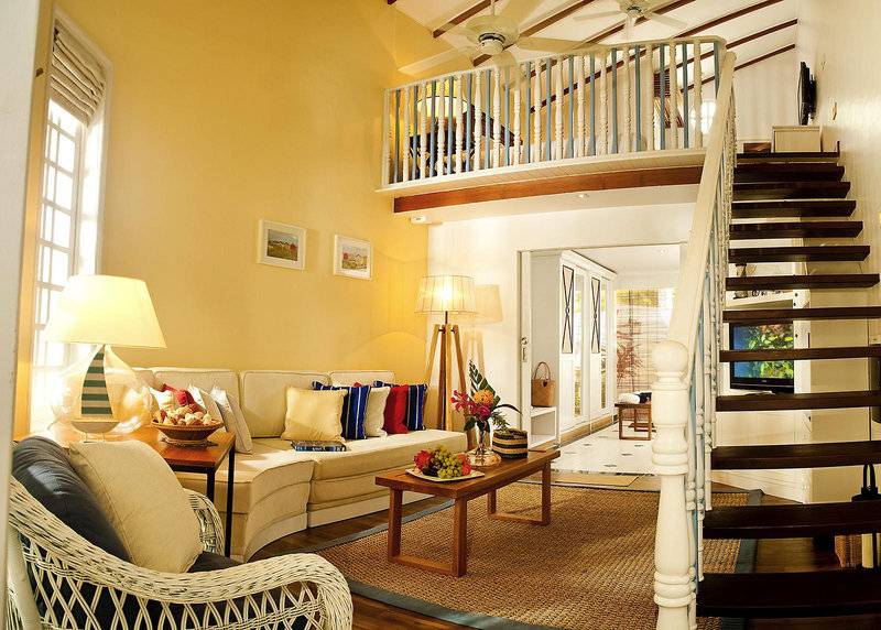 Innenansicht des Wohnbereichs im Centara Grand Island Resort & Spa mit Sofa, Tisch, Lampe und Treppe.