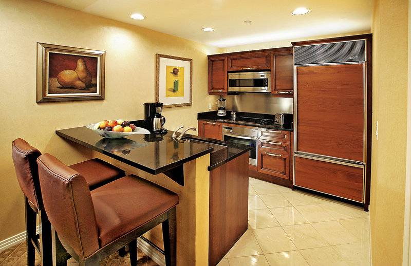 Küche im The Signature At MGM Grand Suite mit Holzschränken und schwarzem Arbeitsbereich.
