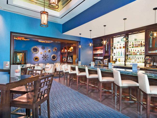 Innenbereich des Signature at MGM Grand Hotel mit Bar, Stühlen und Tischen, blaue Wände und Holzboden.