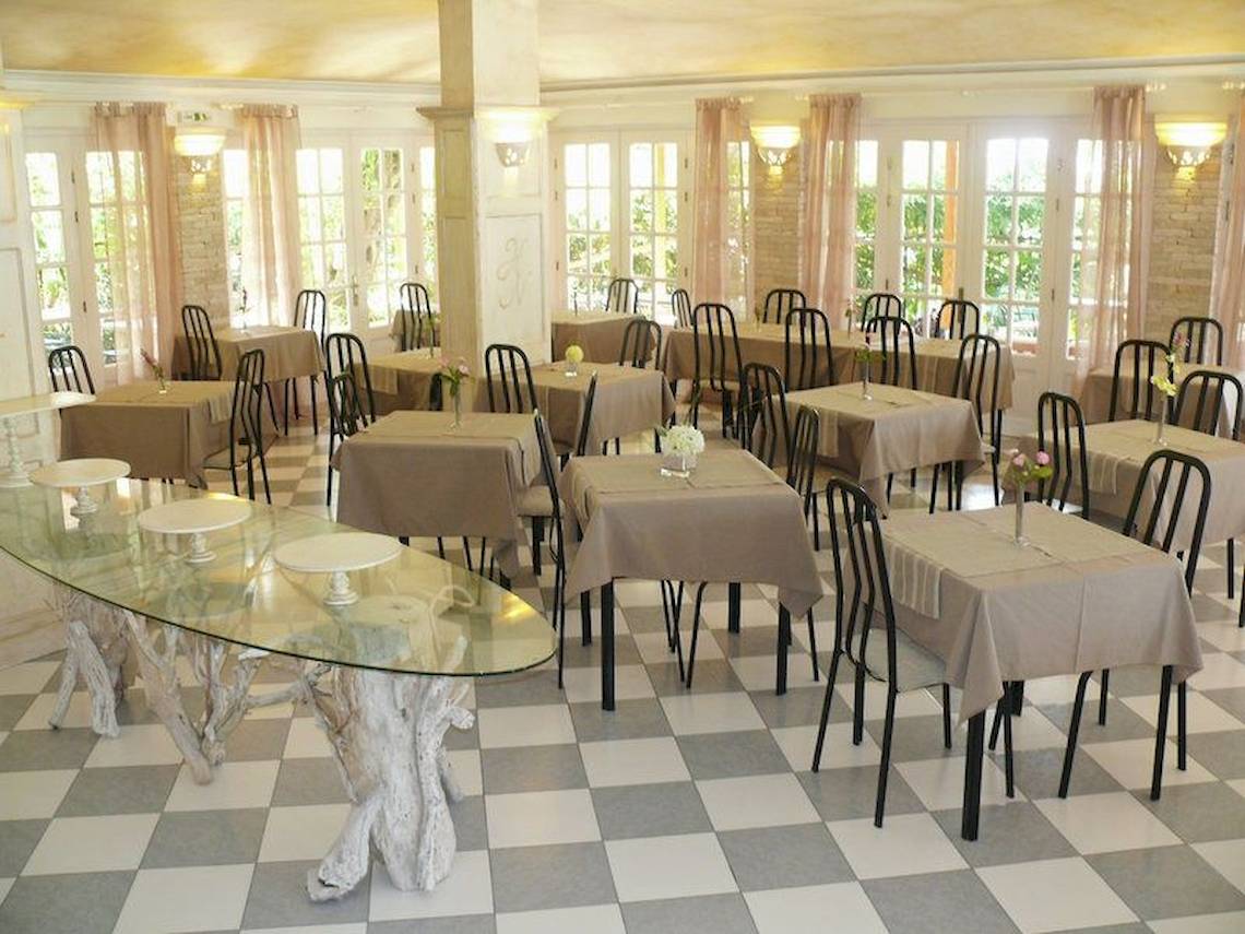 Innenansicht des Restaurants des Nefeli Hotels mit gedeckten Tischen und Stühlen auf einem gemusterten Boden.
