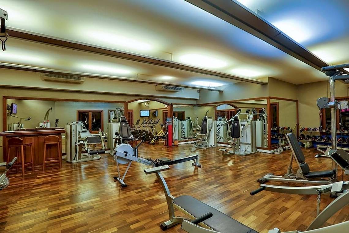 Fitnesscenter im Constance Belle Mare Plage Hotel mit verschiedenen Geräten und Holzböden