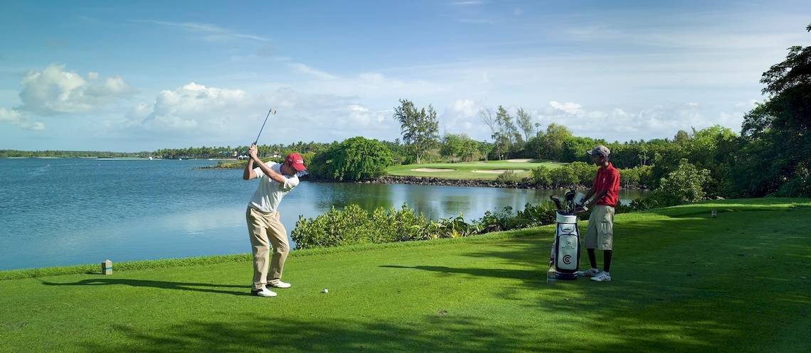 Golfer spielt am Wasser im Constance Belle Mare Plage Hotel.