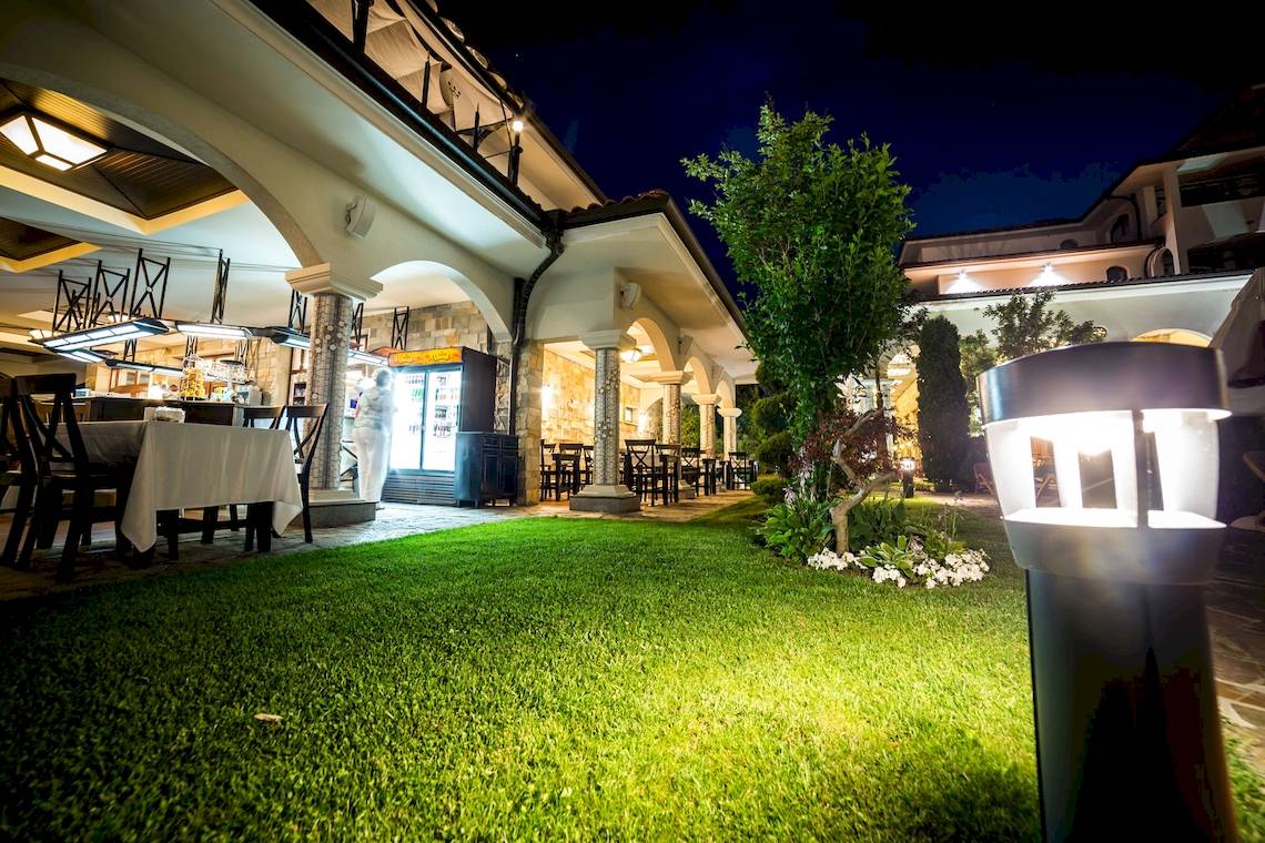 Außenbereich des Helena Sands Hotels bei Nacht mit beleuchteter Terrasse und Grünfläche.