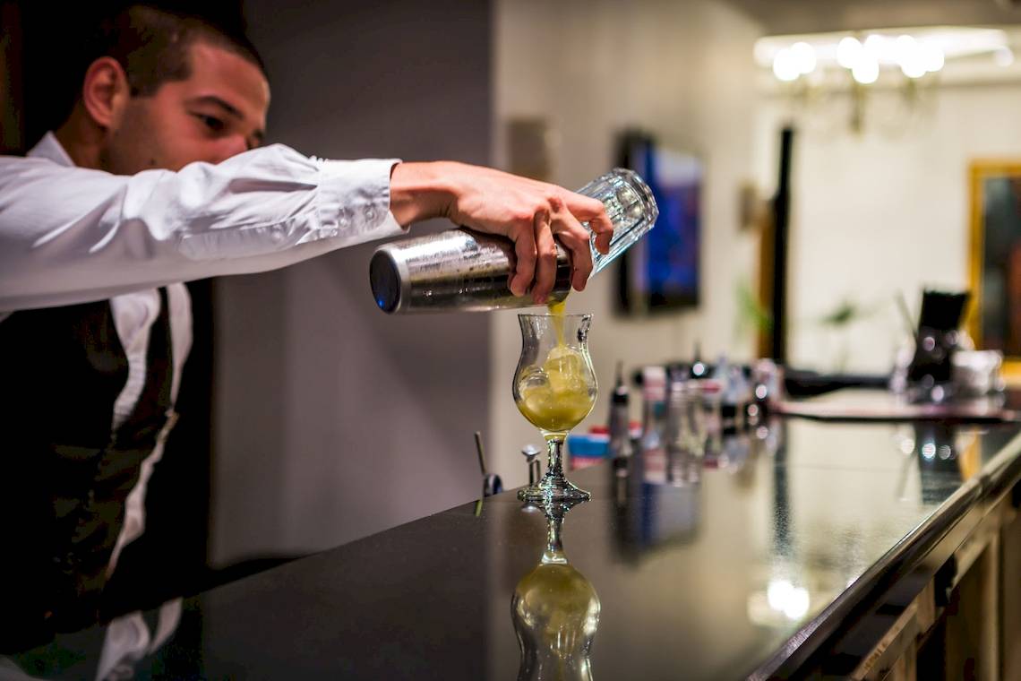 Ein Barkeeper mischt einen Cocktail in einem Glas im Helena Sands Hotel.