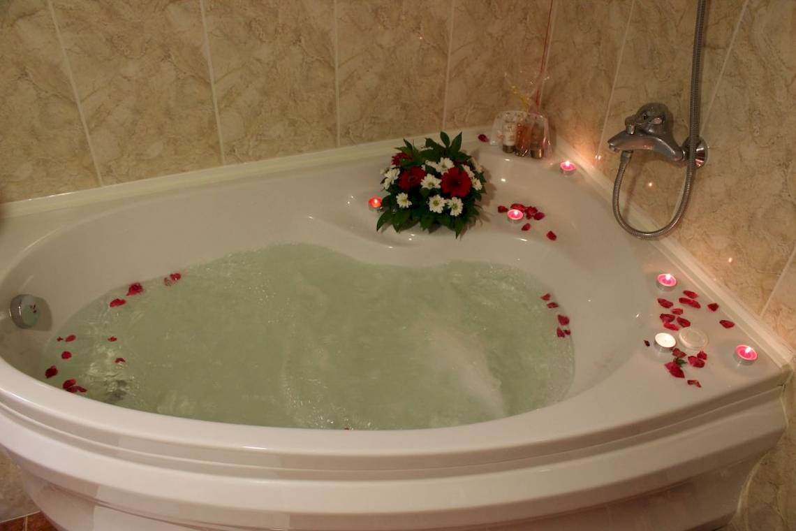 Whirlpool-Badewanne im Helena Sands Hotel mit Blumen und Kerzen.
