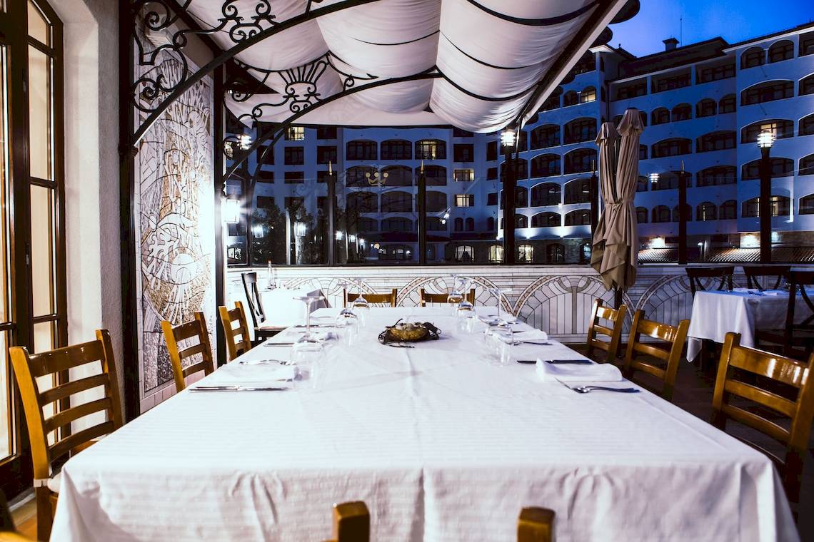 Ein Tisch auf der Terrasse des Helena Sands Hotels, umgeben von kunstvollen Dekorelementen und Blick auf das Gebäude.