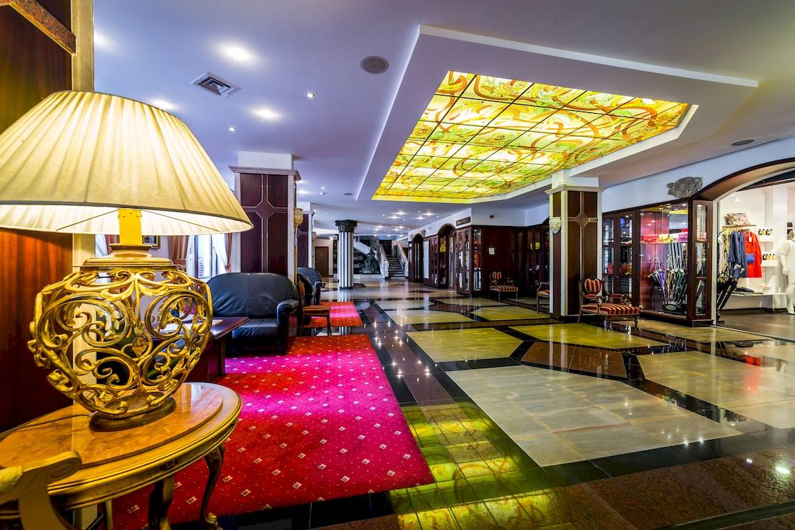Ein Blick in die Lobby des Helena Sands Hotels mit einer großen Lampe und einem roten Teppich.