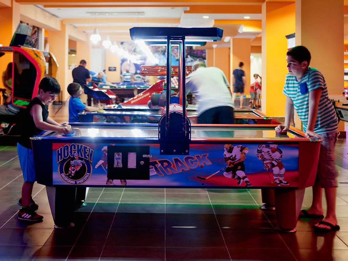 Spielhalle im Sueno Hotels Beach Side mit Kindern, die an einem Hockey-Arcade-Spiel teilnehmen.