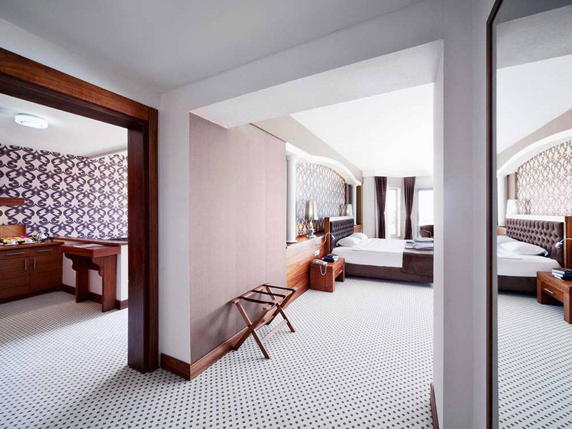 Suite-Zimmer im Sueno Hotels Beach Side mit zwei Betten, Ankleidebereich und Badezimmer.