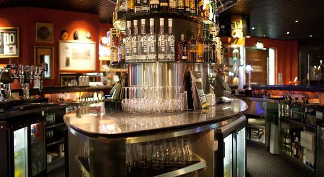 Die Bar im Manzil Downtown by Vida Hotel in Dubai mit verschiedenen Flaschen und Gläsern.