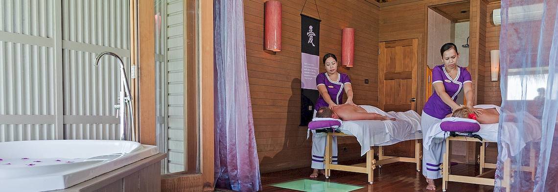 Massagebehandlung im Meeru Island Resort & Spa mit zwei Therapeutinnen und zwei Patienten auf Liegen.