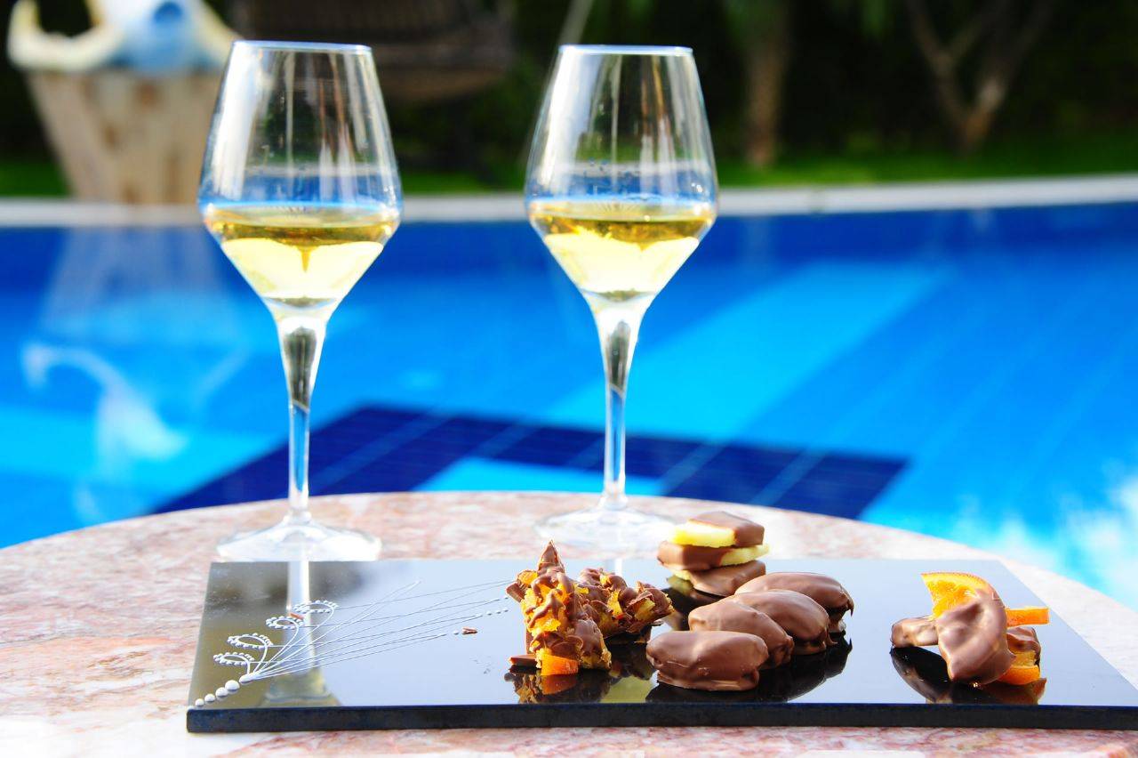 Zwei Gläser Weißwein neben einer Schokoladentafel am Pool des Delphin BE Grand Resort.