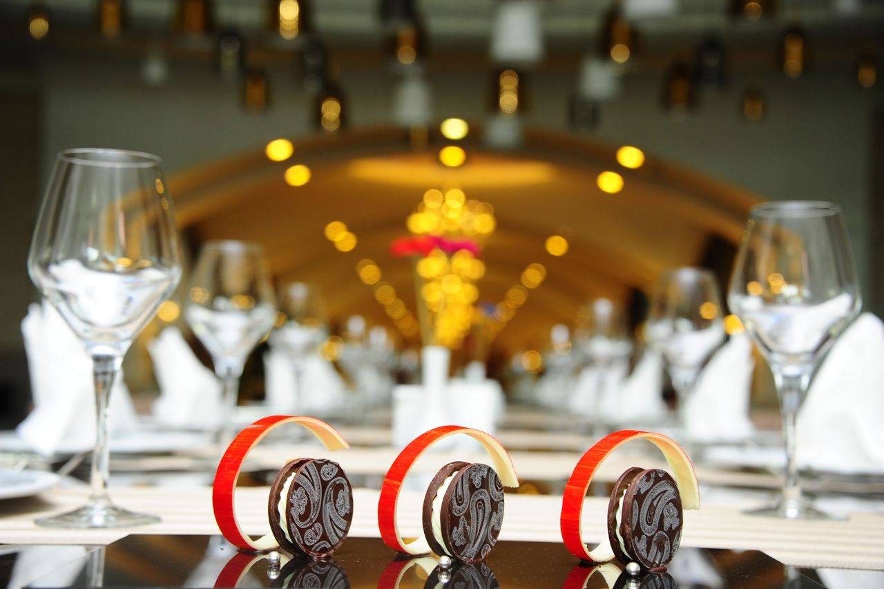 Elegant gedeckter Tisch im Delphin BE Grand Resort mit Gläsern und dekorativen Keks-Kreationen im Vordergrund.