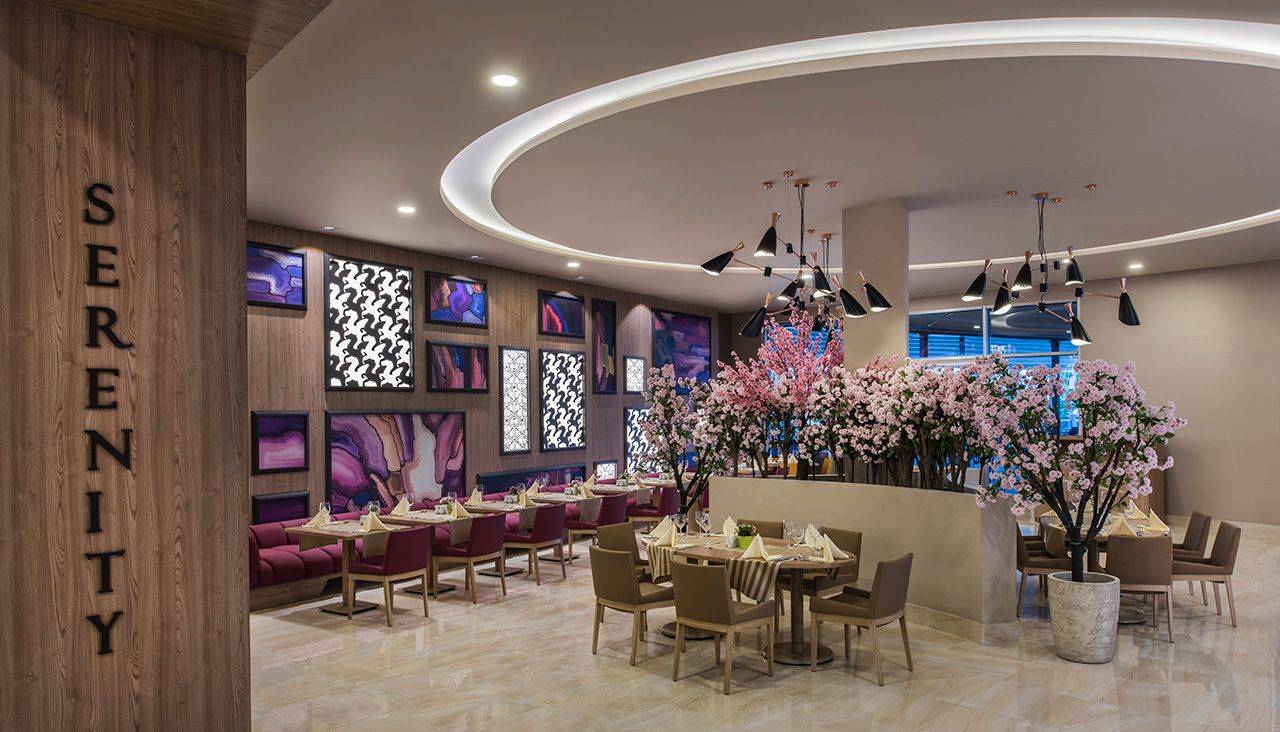 Elegantes Restaurant im Delphin BE Grand Resort mit modernen Möbeln und blühenden Kirschbäumen.