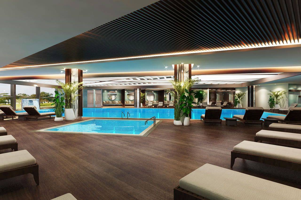 Innenbereich des Delphin BE Grand Resort mit einem Schwimmbad und entspannenden Liegen im Hintergrund.