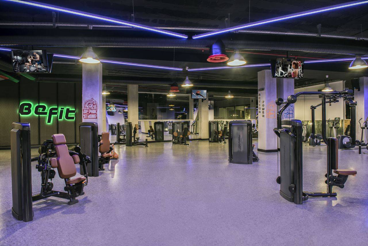 Moderne Fitnessstudio-Ausrüstung im Delphin BE Grand Resort, beleuchtet mit bunten Lichtern und mehreren Bildschirmen.