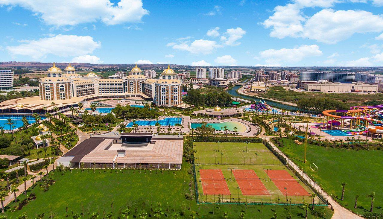 Luftaufnahme des Delphin BE Grand Resorts mit Pools, Tennisplätzen und einem Wasserpark in der Umgebung.