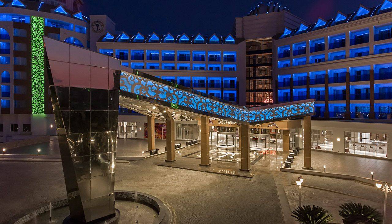 Eingangsbereich des Delphin BE Grand Resorts, beleuchtet mit blauem Licht und modernem Design bei Nacht.