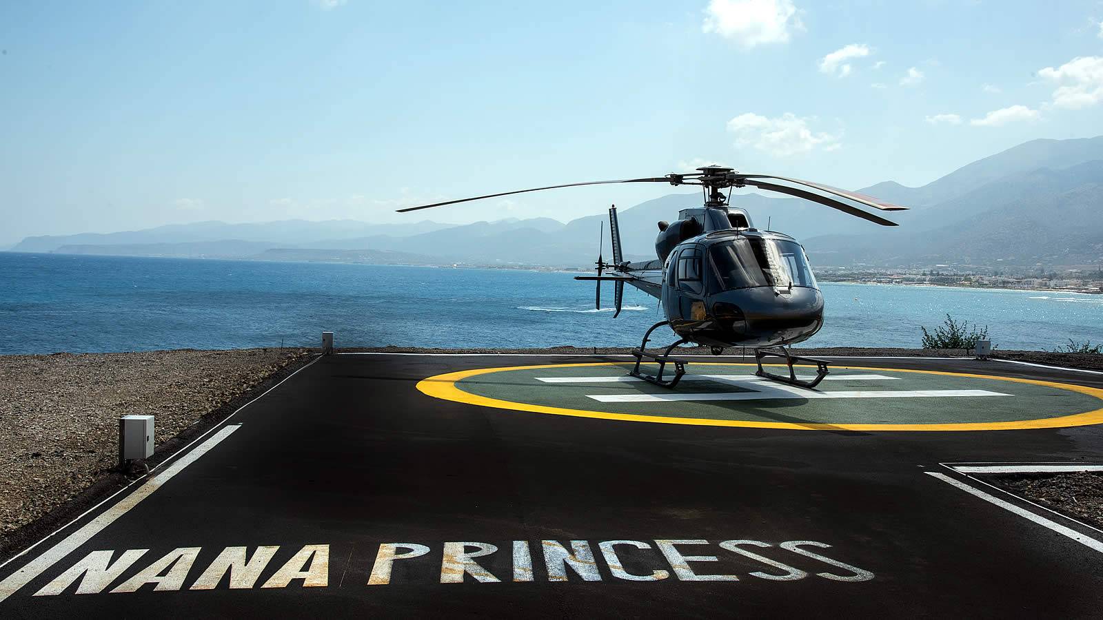 Ein schwarzer Hubschrauber der Nana Princess steht auf einem Landeplatz am Strand.