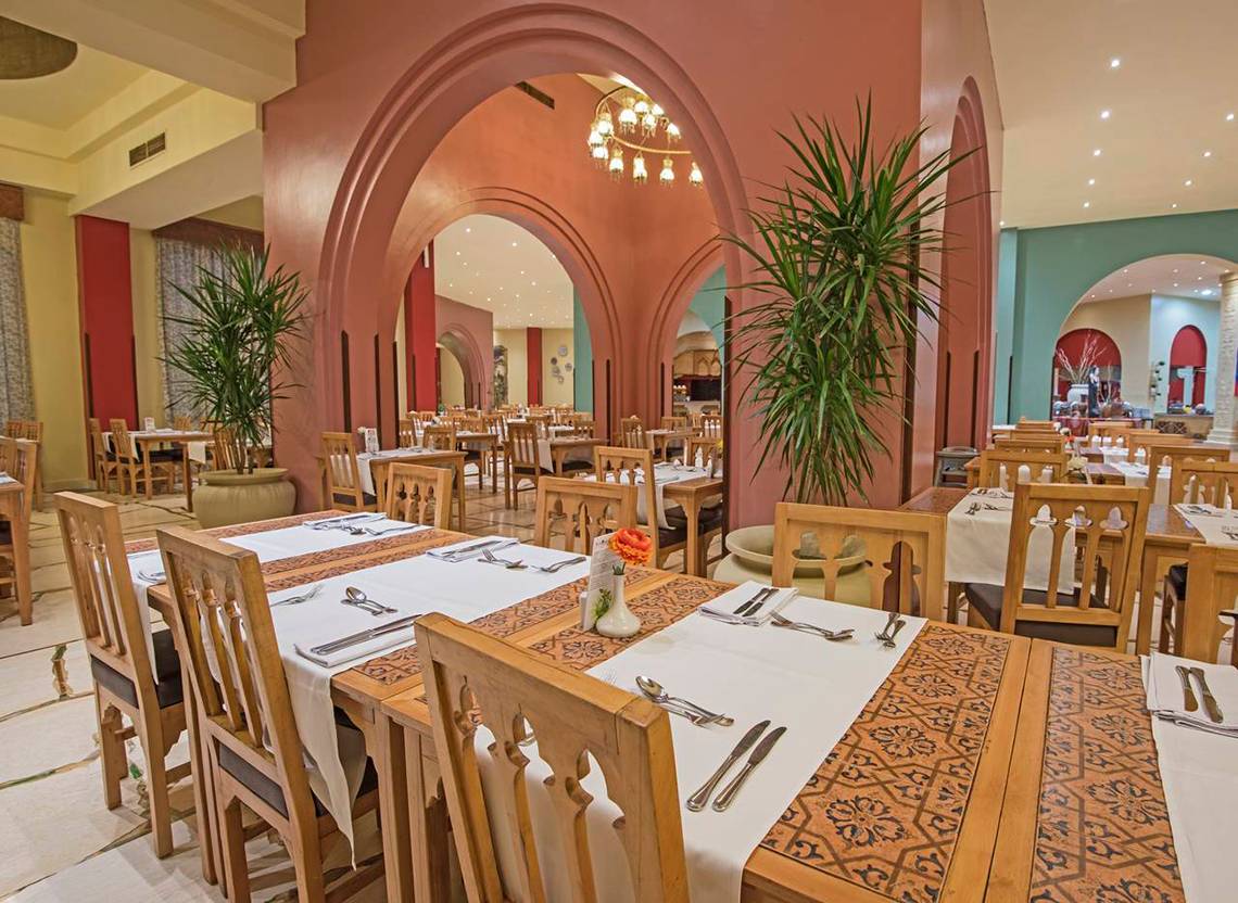 Innenansicht des Restaurants im Sunrise Royal Makadi Resort mit gedeckten Tischen und Stühlen.
