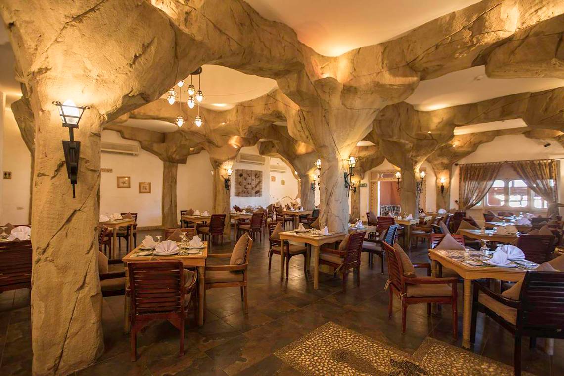 Das geräumige Restaurant im Sunrise Royal Makadi Resort mit steinernen Säulen und Holztischen.