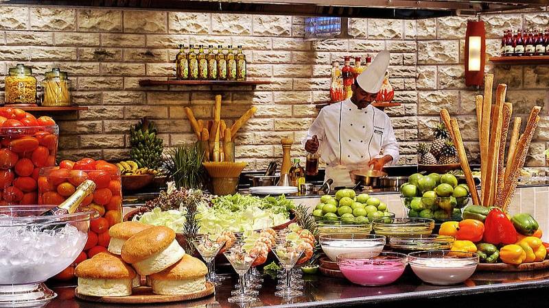 Buffet-Tisch im Diani Reef Beach Resort & Spa mit Salat, Obst und verschiedenen Gerichten.