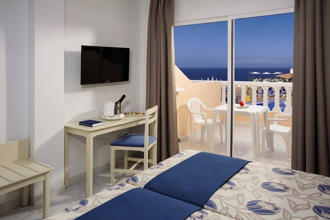 Hotelzimmer mit Meerblick im Bahia Flamingo, inklusive Fernseher und Balkon mit Tisch und Stühlen.
