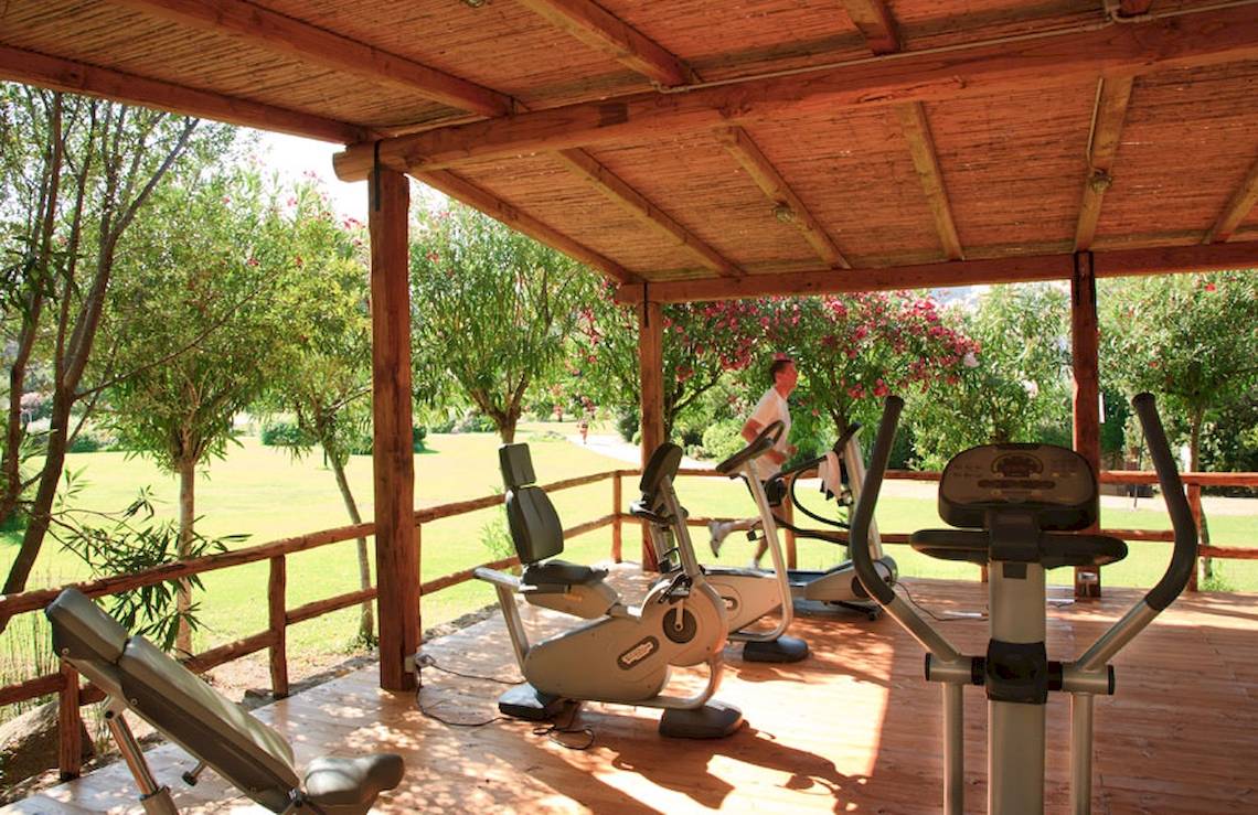 Fitnessbereich im Freien im Hotel Giardini di Porto Cervo mit Geräten und einem Mann, der läuft.