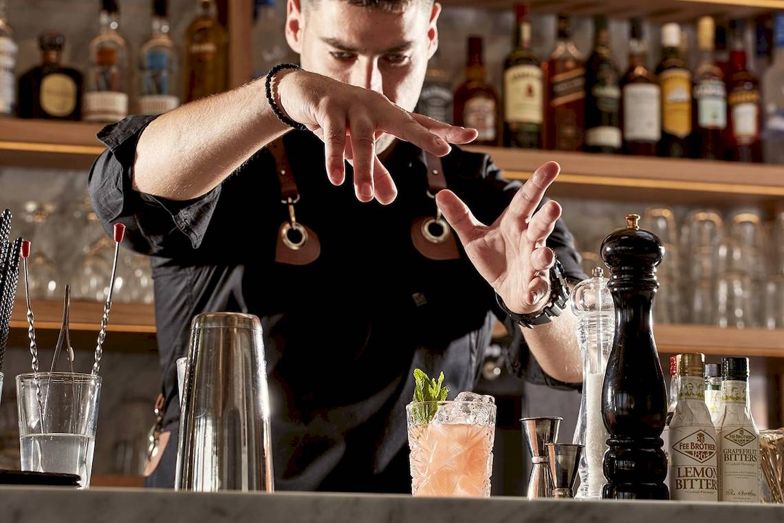 Barkeeper bei der Arbeit im Mykonos Ammos Hotel, der einen Cocktail mit einer Minzblattgarnitur zubereitet.