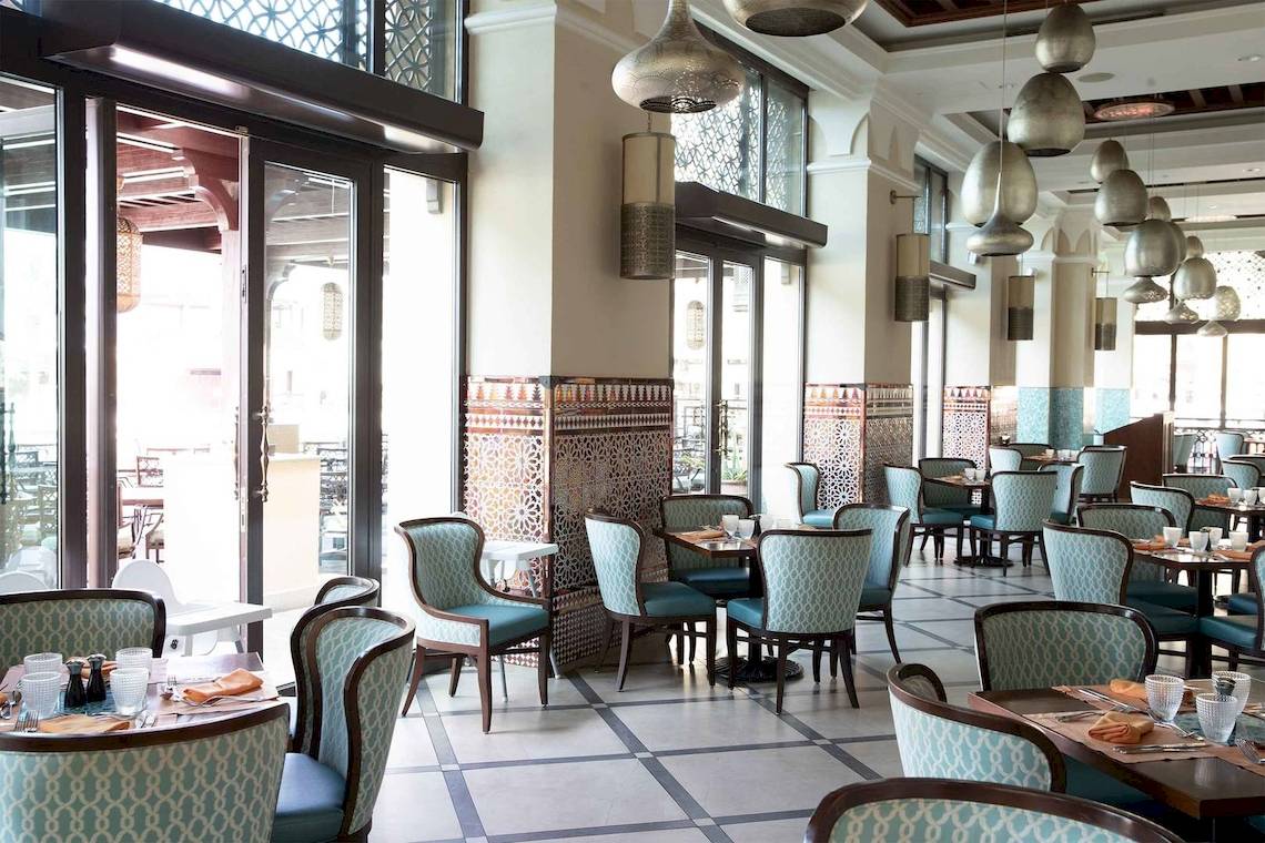 Innenansicht des Restaurants im Jumeirah Mina A'Salam Hotel mit modernen Möbeln und Glastüren.