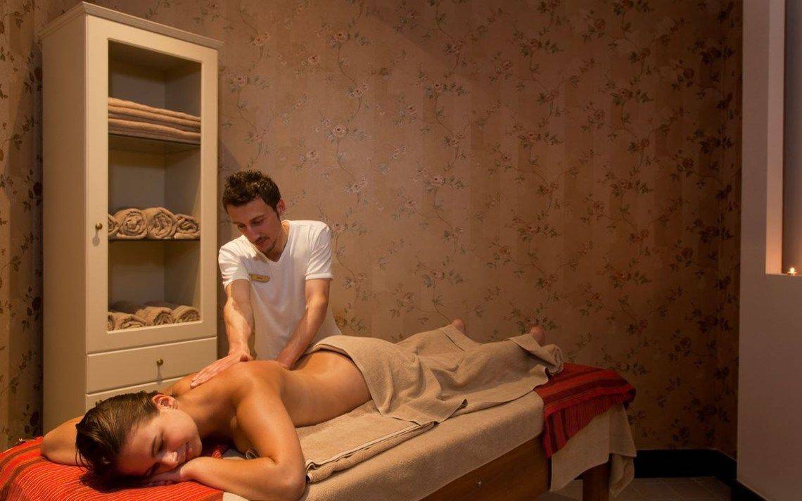 Massagebehandlung im Oz Hotels Side Premium mit einem Mann, der eine Frau auf einer Massageliege massiert.