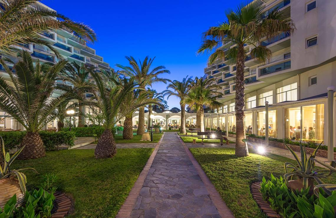 Apollo Beach Hotel Eingang mit Palmen und Gehweg bei Nacht