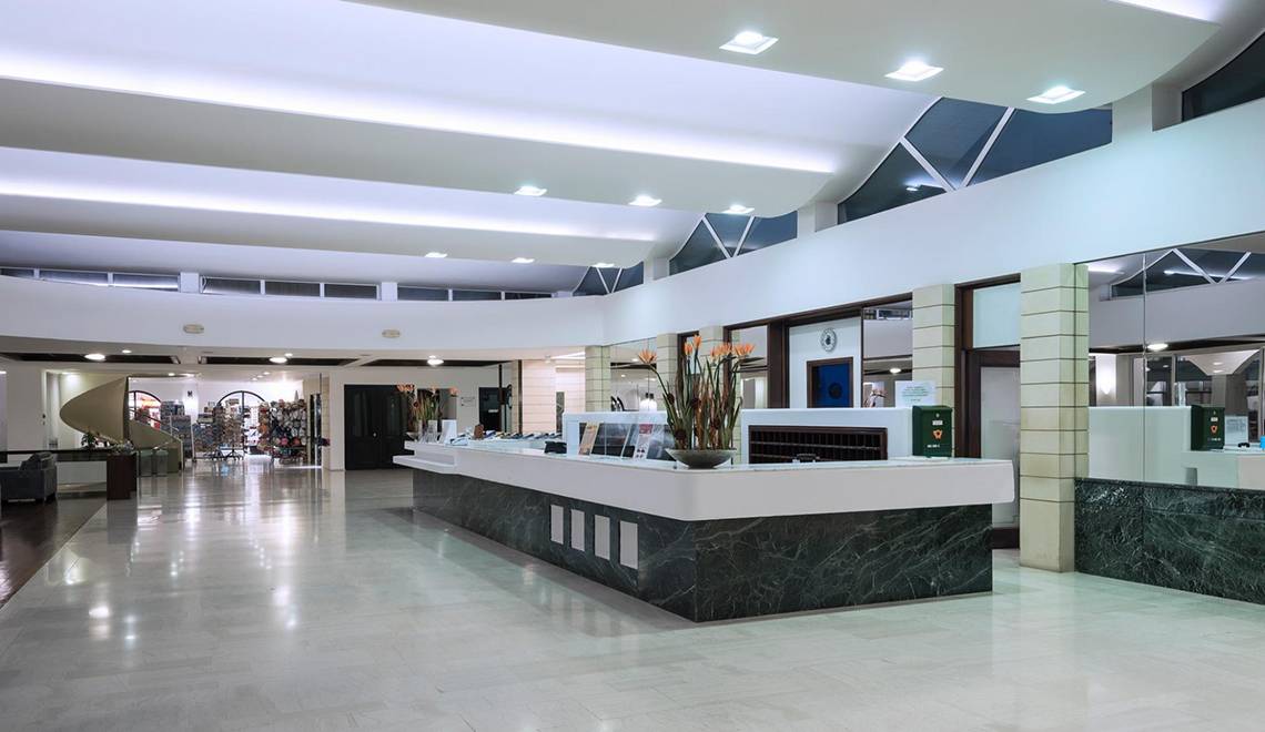Empfangsbereich des Apollo Beach Hotels mit moderner Einrichtung und Marmor-Theke.