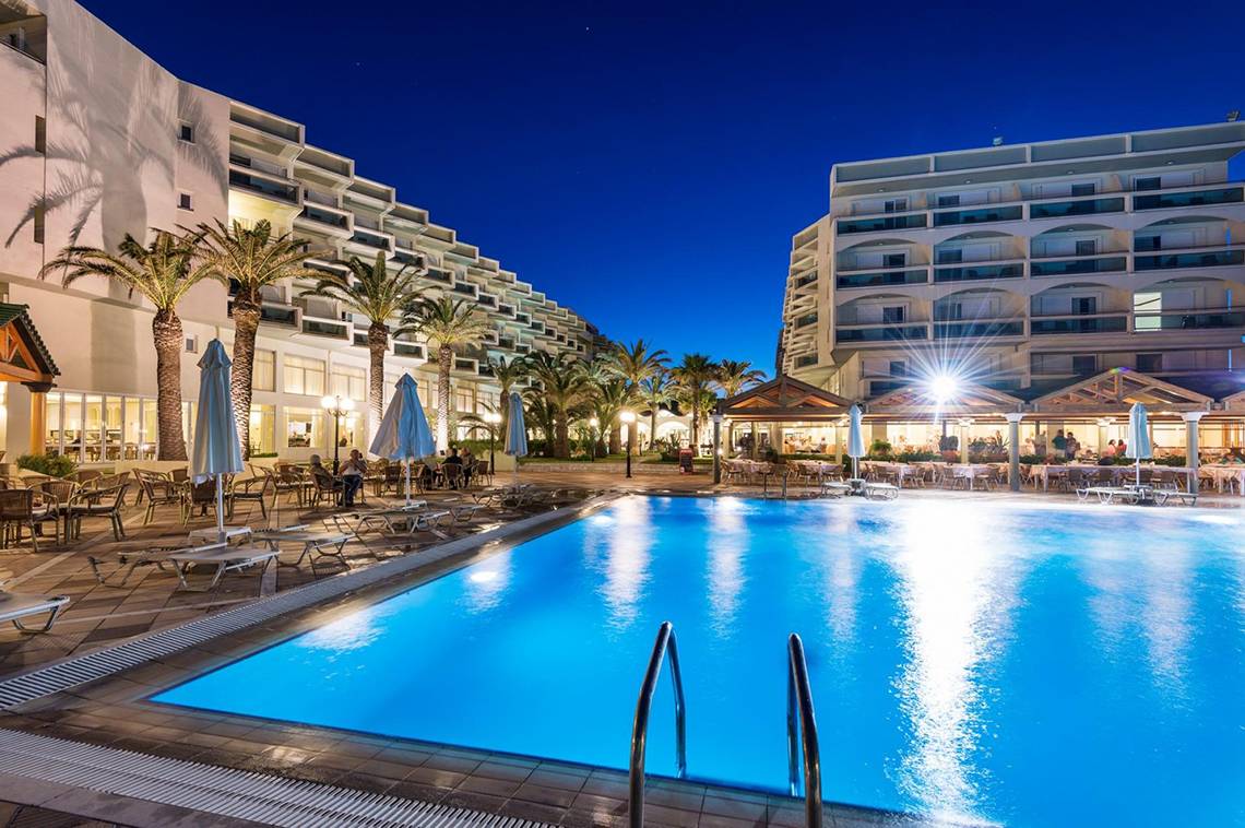 Außenpool des Apollo Beach Hotels bei Nacht mit beleuchteten Gebäuden und Sitzgelegenheiten
