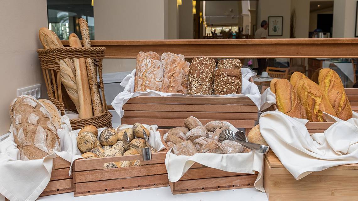 Brotbuffet im Apollo Beach Hotel mit verschiedenen Brotsorten in Holzkörben auf einem Tisch.