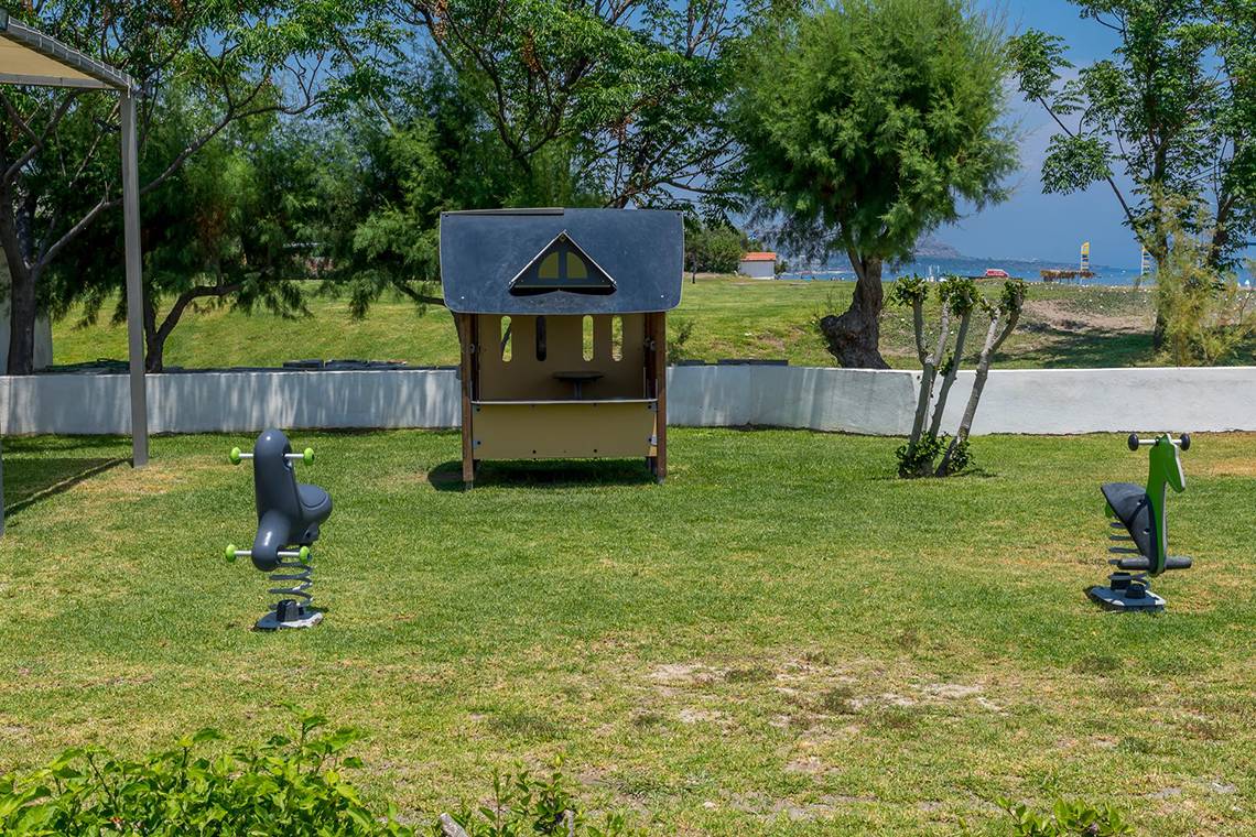 Spielplatz im Freien im Apollo Beach Hotel mit Hüttchen und Spielgeräten.
