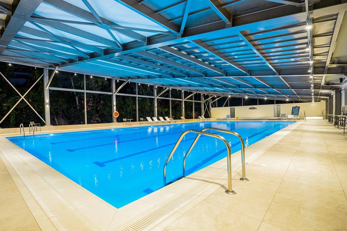 Innenpool des Apollo Beach Hotels mit blauem Wasser und Edelstahlhandläufen