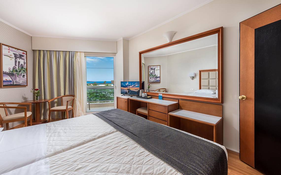 Doppelzimmer mit Meerblick im Apollo Beach Hotel, mit zwei Betten, Schreibtisch und Aussichtsfenster.