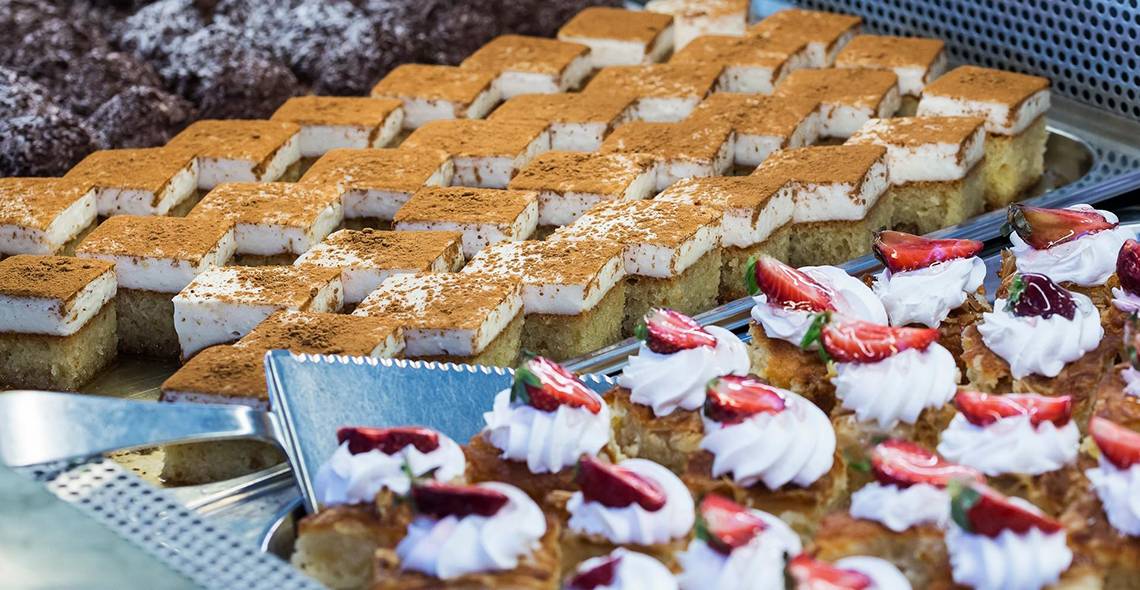 Eine Auswahl an verschiedenen Desserts im Apollo Beach Hotel, darunter Kuchen und Gebäck mit Sahne und Früchten.