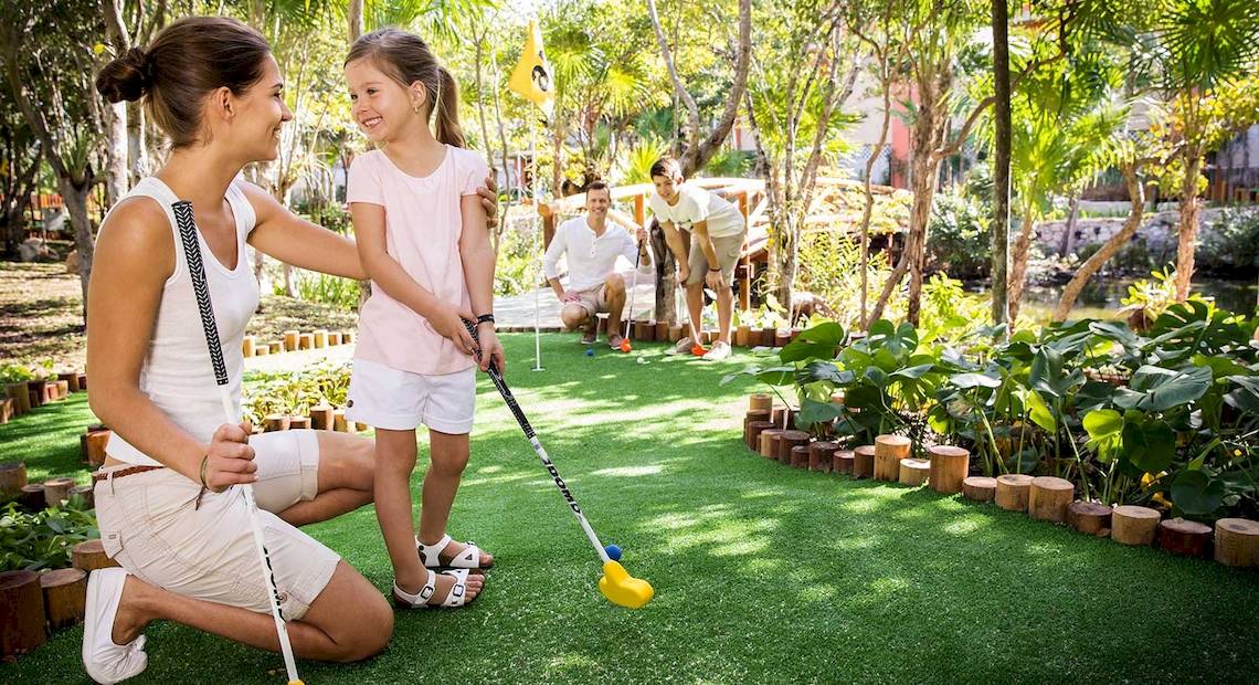 Eine Familie spielt Putt-Golf im Freien im Barcelo Maya Grand Resort.