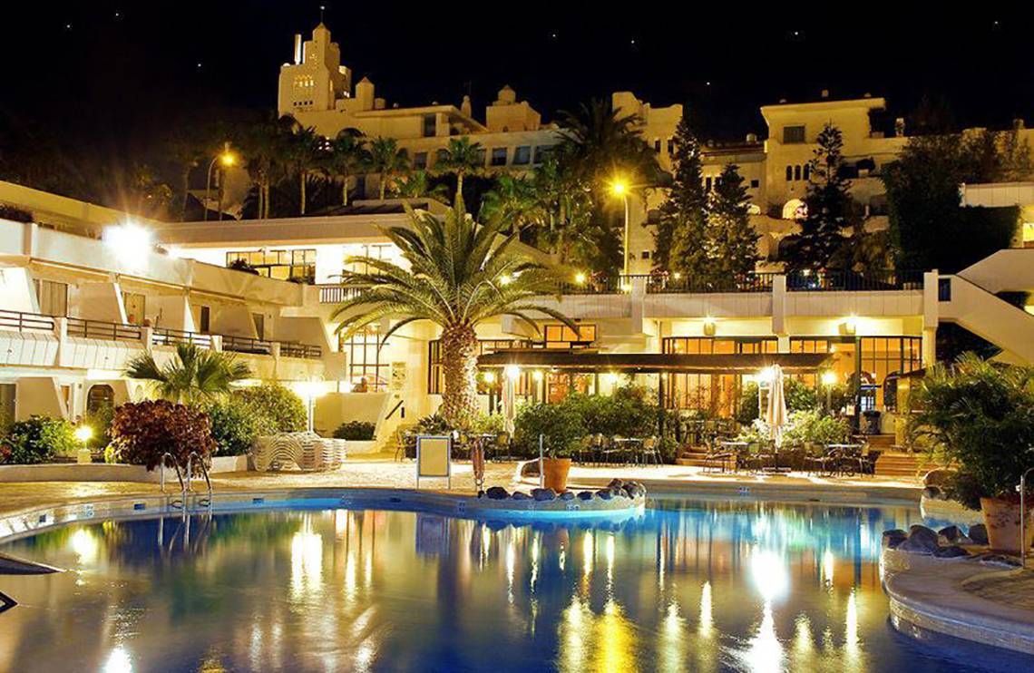 Nachtansicht des Hovima Panorama Hotels mit beleuchtetem Pool und Gebäuden im Hintergrund.